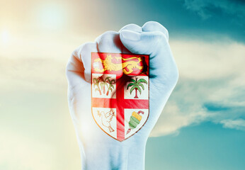 Fiji national flag fist raise in the sky. The hand with flag raise in beautiful soft sky. Fiji national flag for independence day.