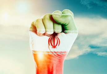 Iran national flag fist raise in the sky. The hand with flag raise in beautiful soft sky. Iran...