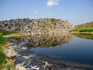 massive illegal dumping site next to a contaminated ditch containing dark, toxic leachate water...