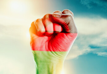 Malawi national flag fist raise in the sky. The hand with flag raise in beautiful soft sky. Malawi national flag for independence day.