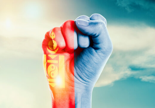 Mongolia national flag fist raise in the sky. The hand with flag raise in beautiful soft sky. Mongolia national flag for independence day.