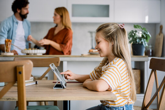 Child using digital tablet for learning at home in kitchen