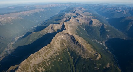 Aerial view showcases a vast mountain range with valleys and lush forests under a bright sky