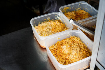 Street food kitchen with prepared noodles in plastic containers