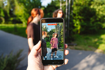 Friends creating social media content outdoors with smartphone recording