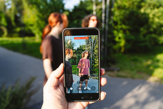 Friends creating social media content outdoors with smartphone recording