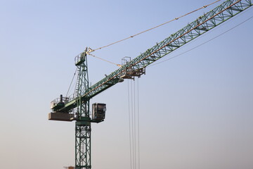 Green tower crane against blue sky