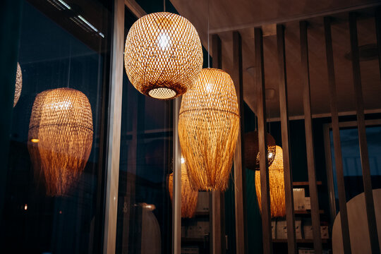 A row of wooden lamps with a warm glow. The lamps are hanging from the ceiling and are lit up.