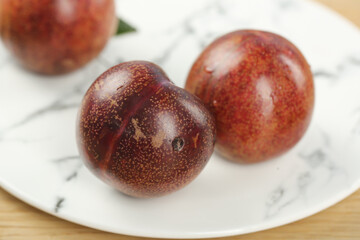 Obraz premium Fresh Red Plums on White Plate - Healthy Organic Stone Fruit for Natural Diet and Nutrition