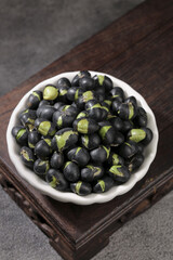 Crispy Fried Black Beans with Green Herbs and Salt in White Bowl on Wooden Tray