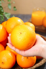 Fresh Sweet Navel Orange from Zigui Gannan Alpine Region in Hand with Orange Juice Glass