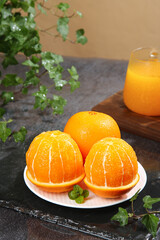 Fresh Peeled Navel Oranges with Orange Juice and Mint on Dark Stone Surface