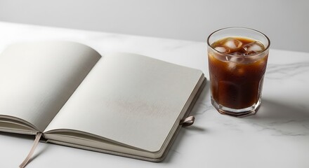 밝은 대리석 위에 놓인 빈 노트와 시원한 아이스 커피의 평화로운 순간