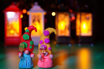 Two toy gnomes with glasses of champagne and New Year's burning lanterns.