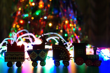Wooden Christmas train on the background of a Christmas tree garland.