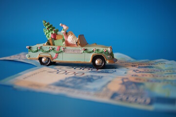 A toy car with Santa and money on a blue background.