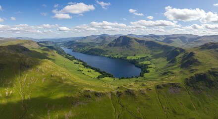 Aerial vista of a serene lake nestled amidst rolling green hills and majestic mountain ranges under a blue sky