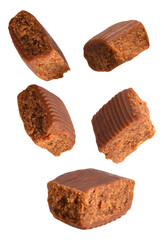 a photograph showing five individual pieces of rich, dark brown, textured fudge or soft caramel toffee candy dynamically falling against a black backdrop.