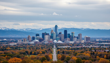 Sweeping view of city skyline with autumn trees and mountains under cloudy sky