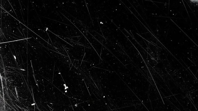 Abstract black background with distressed texture featuring numerous random scratches and speckles, creating an aged, worn aesthetic.