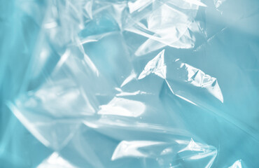 Close-up of crumpled translucent blue plastic with light reflections, creating an abstract and modern background.