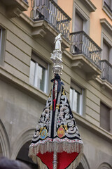 Silver processional staff topped with a statue and decorated embroidered banner, carried through the streets during a religious event. Granada, tradition