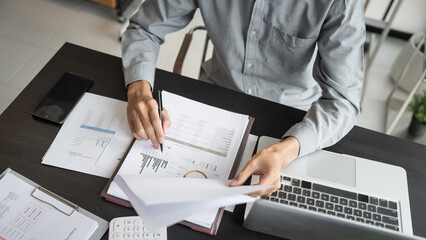Asian business man holding paper document calculating tax insurance managing budget