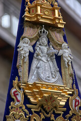 Silver relief of the Virgin and Child with angels on a richly embroidered velvet banner during the Granada procession. Devotion, heritage.