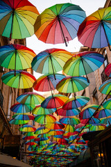 Colorful umbrellas create a vibrant atmosphere in a narrow street in an urban area during dusk