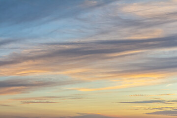 Dramatic evening sky displaying vibrant colors and dynamic cloud formations over a tranquil landscape during sunset
