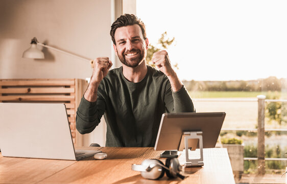 Successful happy freelancer cheering at desk
