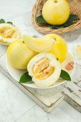 Fresh Yellow Star Melon Slices with Green Leaves on Rustic White Wood Background