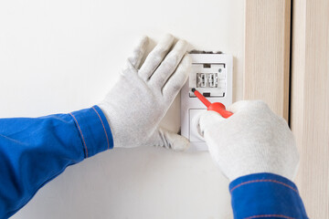 The master uses a screwdriver to install the light switch and socket, close-up.
