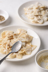 Farfalle pasta with white cream cheese sauce and black pepper, Italian food on a white plate