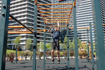 Teen boy doing pull-ups on monkey bars at a modern outdoor workout park in an urban residential area. Healthy lifestyle and active childhood in the city. Sunny day fitness.