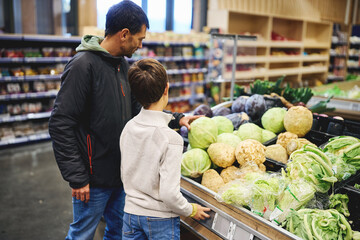 Father and son choosing fresh vegetables in supermarket