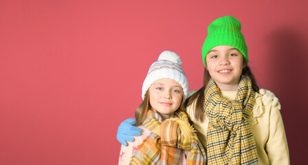 Two friends teenagers 10-12 years old together winter clothes portrait on dark peach background