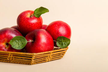 Ripe garden apple fruits with leaves in basket on wooden table. Top view flat lay with copy space