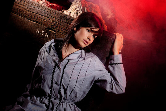 Young woman emerging from darkness in red light