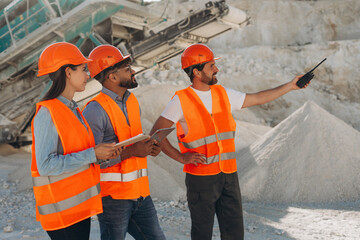 Diverse group of smiling construction workers in safety vests talking and smiling at quarry