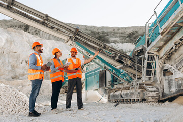 Group of team of architects and engineers planning project outdoors wearing orange helmet and vests