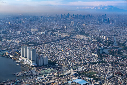 Dense northern Jakarta coastline seen from above, showing rapid urban expansion along the shore as rising sea levels and climate risks threaten low lying districts and future city resilience.