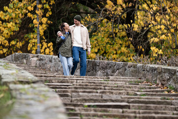 Loving couple walking up park stairs during autumn