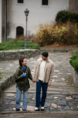 Obraz premium Happy multiracial couple walking hand in hand on city stairs