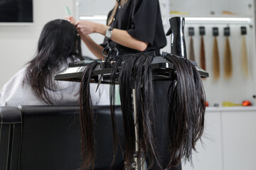 Hair extensions bundles and tools on salon trolley with stylist preparing installation