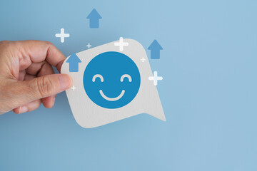 hand hold real white speech bubble paper cut with happy smile face and mental health recovery emotional healing, positivity, self care, and personal growth on blue background