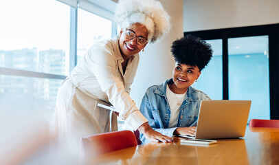 Two women collaborate at a desk in office