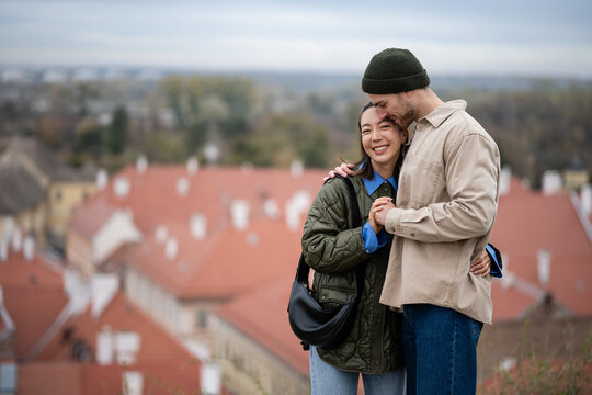 Loving multicultural couple embracing with cityscape view