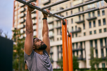 Man Doing Pull-Ups At Outdoor Gym In City Park For Strength Training