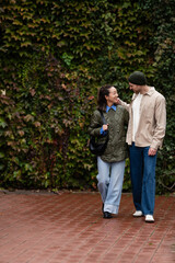Diverse couple walking together on brick pavement with ivy wall